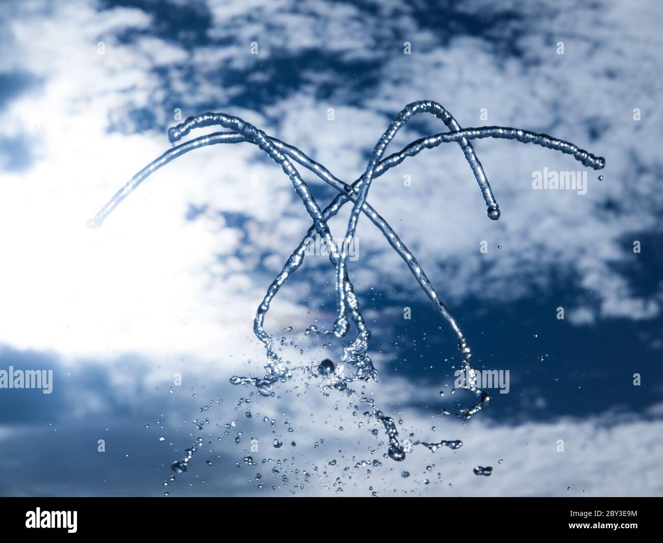 Brunnen frisches Wasser spritzen auf heißen Sommer Himmel Hintergrund. Klares Wasser oder Erfrischungsgetränk. Stockfoto
