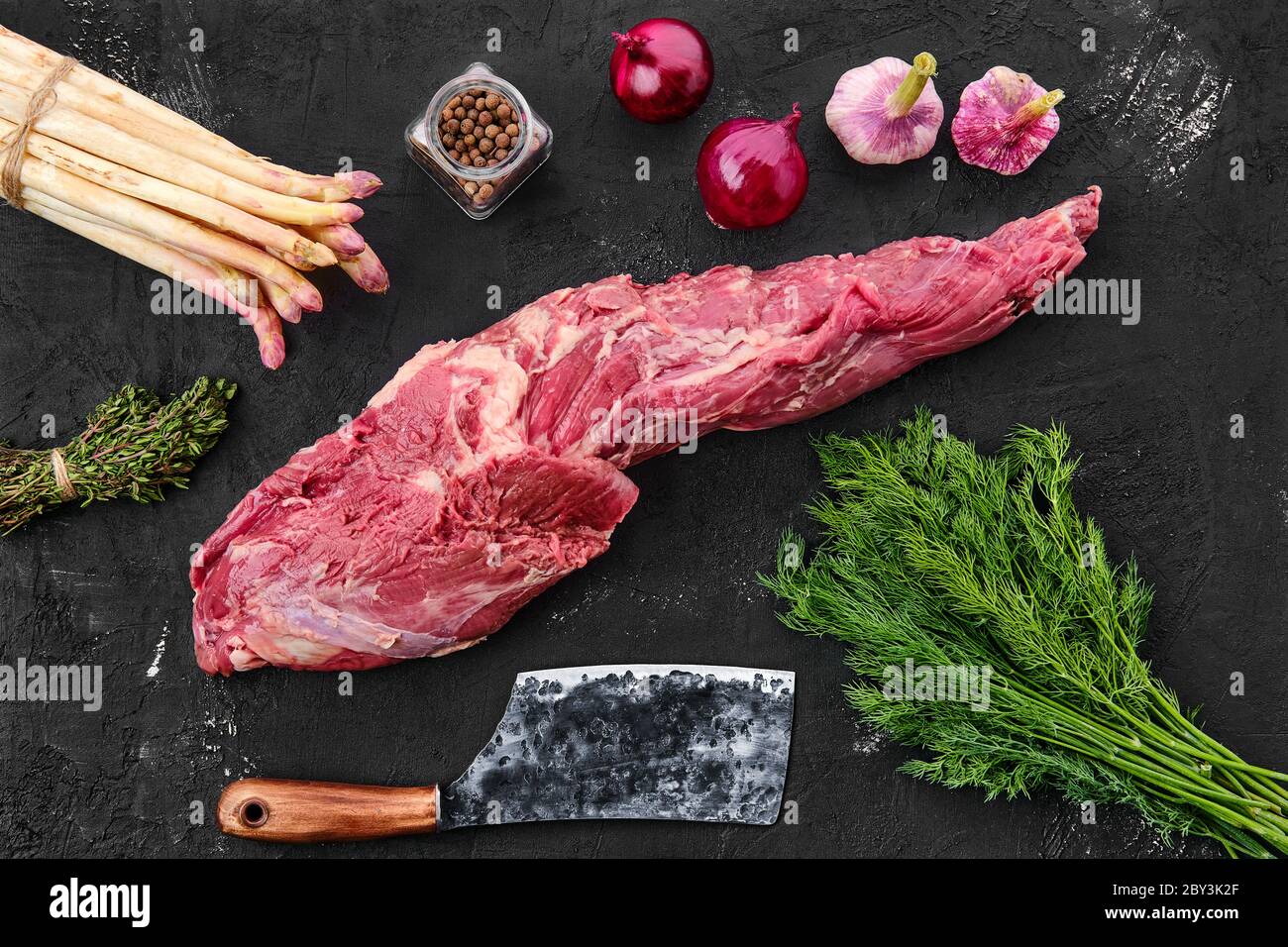Rohes frisches Rindfleisch ganze Filet mit Gewürzen auf schwarzem Hintergrund Stockfoto