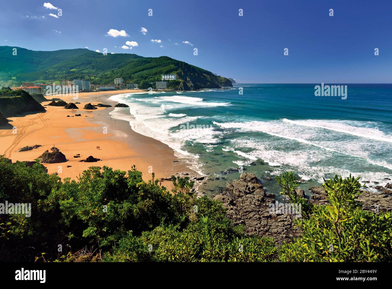 Blick auf schönen Strand mit großem Sandareal, Felsen und grünen Hügeln im Hintergrund. Stockfoto