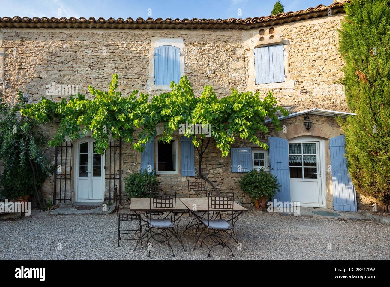 Ein typisches französisches Haus in der Provence, mit blauen Fensterläden und einem Essbereich im Freien Stockfoto