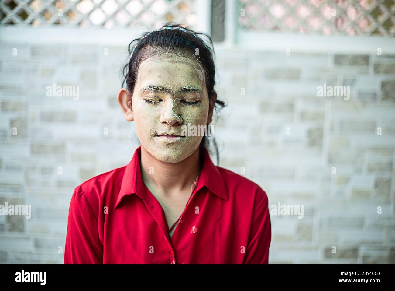 Junge Brünette Mädchen mit ayurvedischen natürlichen herbal kosmetische Gesichtsmaske über ihr Gesicht aufgetragen. multani mitti / Fuller Erde Ton Pack Stockfoto