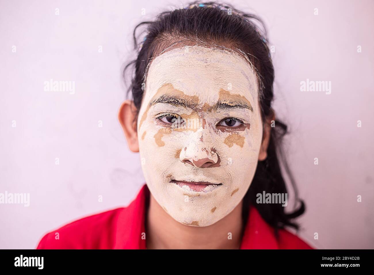 Junge Brünette Mädchen mit ayurvedischen natürlichen herbal kosmetische Gesichtsmaske über ihr Gesicht aufgetragen. multani mitti / Fuller Earth Clay Pack Stockfoto