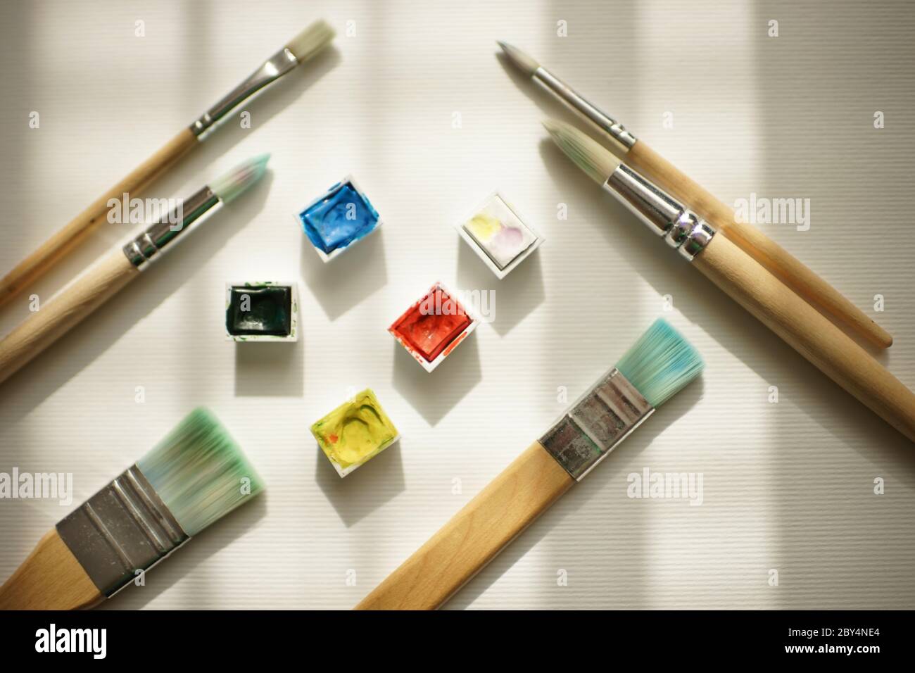 Aquarellfarbe und verschiedene Pinsel auf weißem Papier. Stockfoto
