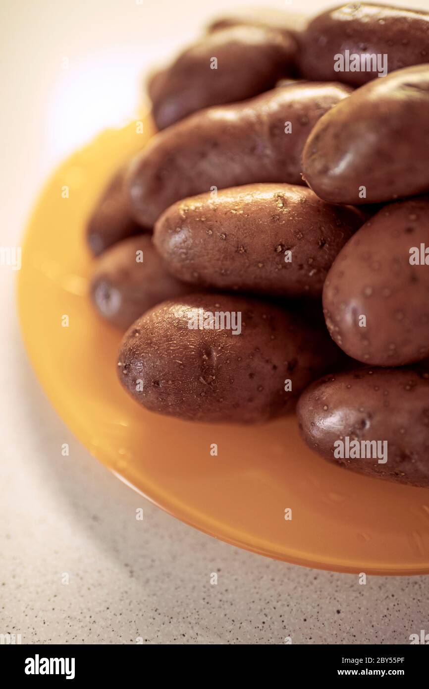 Ganze rohe Kartoffeln in einer Schale auf einem Orangenplatte. Stockfoto