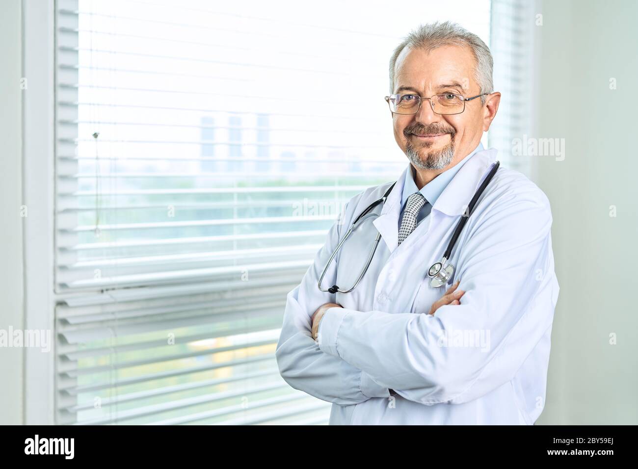 Fröhliche reife Arzt posing und lächelnd an Kamera, Gesundheitswesen und Medizin. Stockfoto