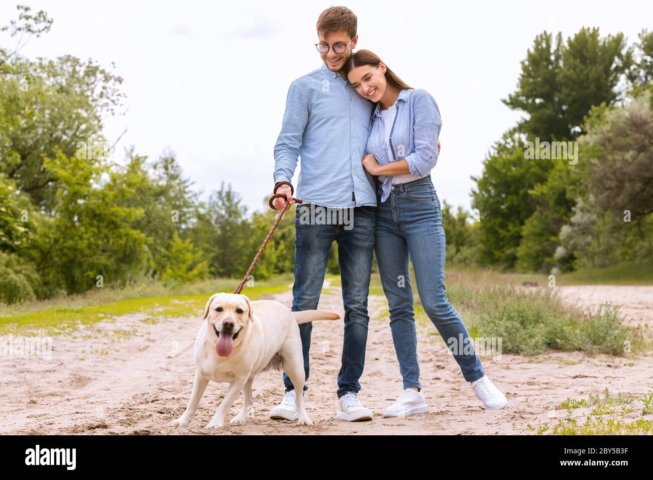 Porträt von glücklichen jungen Paar zu Fuß ihren schönen Hund Stockfoto