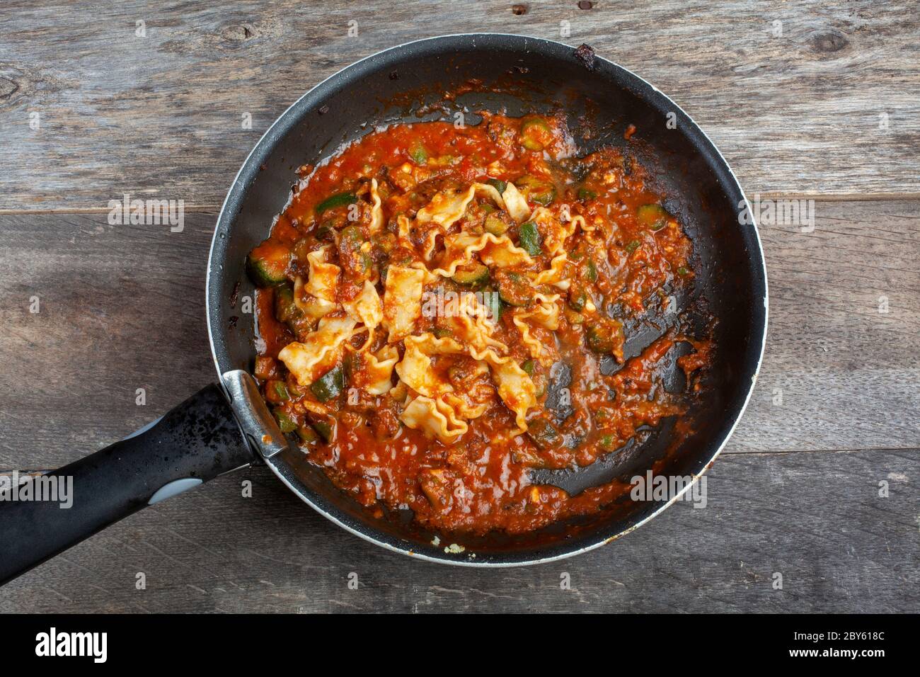 Studioaufnahme von Drill Noodles mit Kürbissen in einer Pfanne auf Holzhintergrund Stockfoto