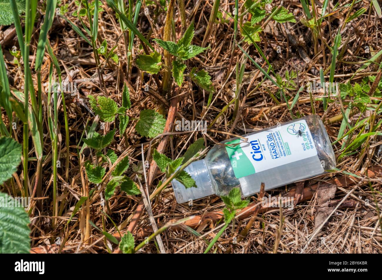 Der neue Müll - eine leere Flasche Handdesinfektionsmittel, die an einem Straßenrand weggeworfen wird. Stockfoto