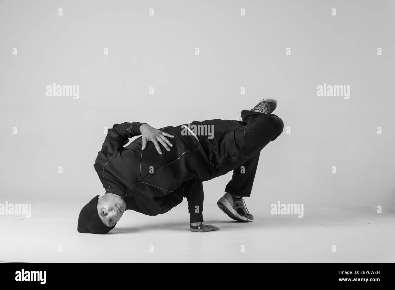 Ein Mann Hip Hop Tänzer oder bboy friert in einer Pose auf weißem Hintergrund. Bboy macht stylische Stunts. Stockfoto