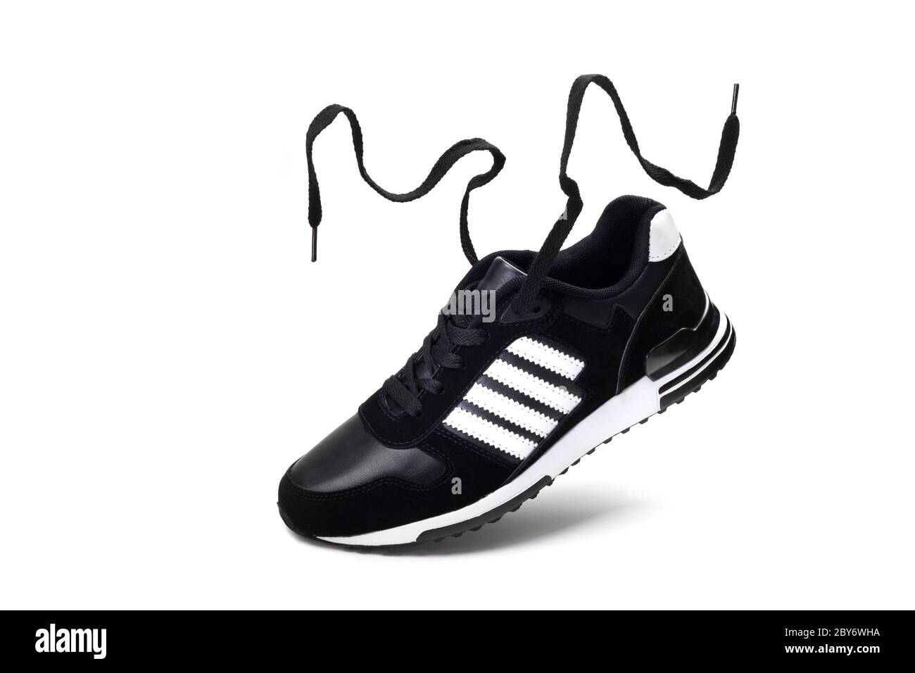Schuhe für den Sport. Fliegender schwarzer Laufschuh für Herren mit flatternden Schnürsenkeln auf weißem Hintergrund. Stockfoto