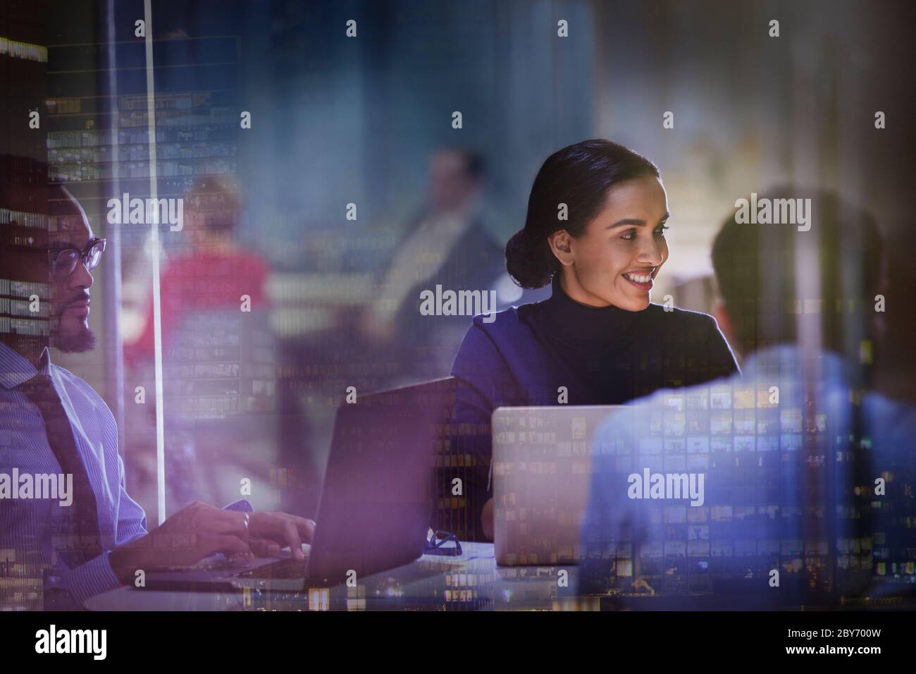 Lächelnde Geschäftsfrau am Laptop bei der Besprechung im Hochhaus Stockfoto
