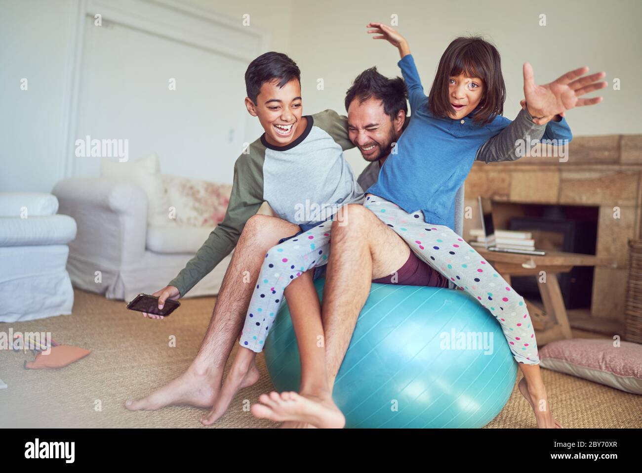 Portrait glückliche Familie spielen auf Fitness-Ball im Wohnzimmer Stockfoto