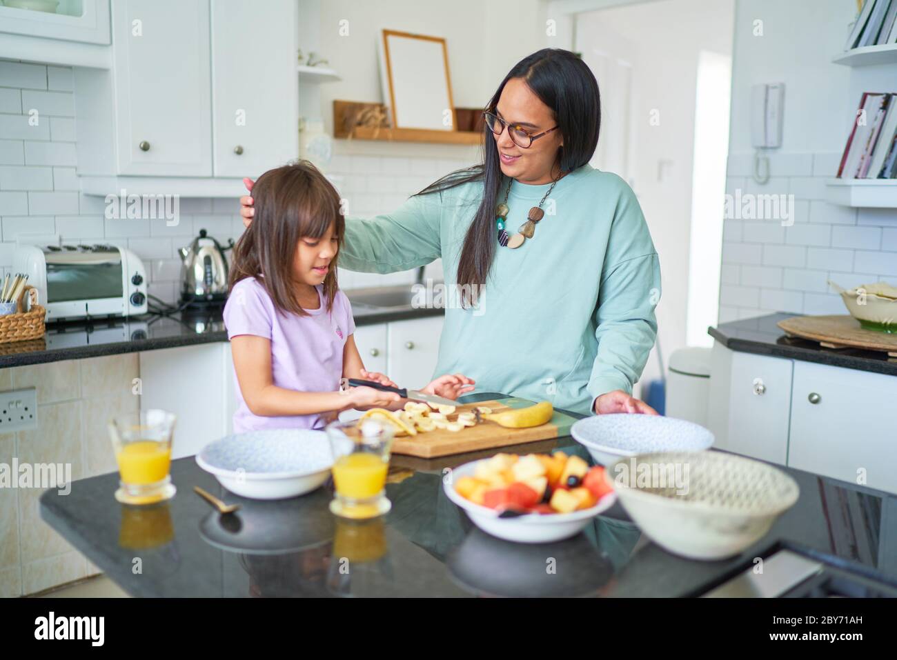 Mutter und Tochter schneiden Bananen in der Küche Stockfoto