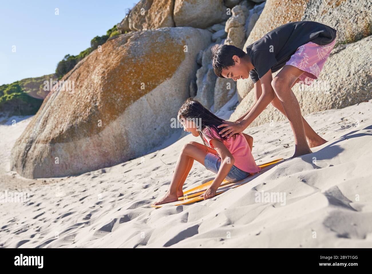 Bruder und Schwester spielen im Sand am sonnigen Strand Stockfoto