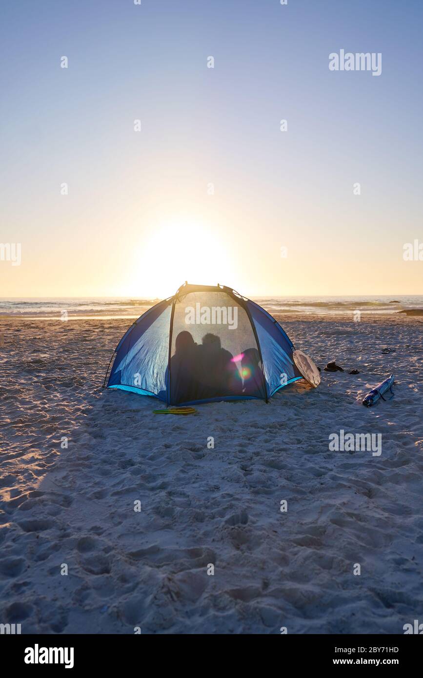 Silhouette Familie im Zelt am sonnigen Sonnenuntergang Strand Stockfoto