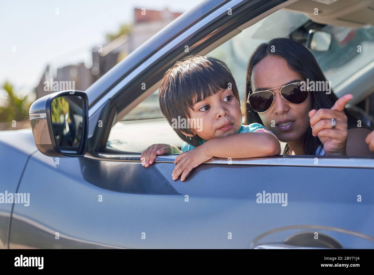 Mutter und Sohn blicken aus dem sonnigen Autofenster Stockfoto