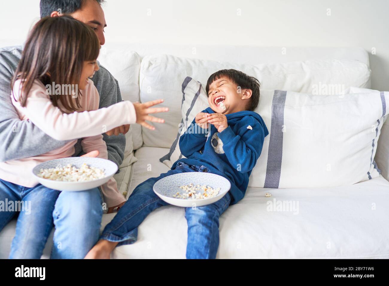 Verspielte Familie mit Popcorn auf dem Wohnzimmersofa Stockfoto
