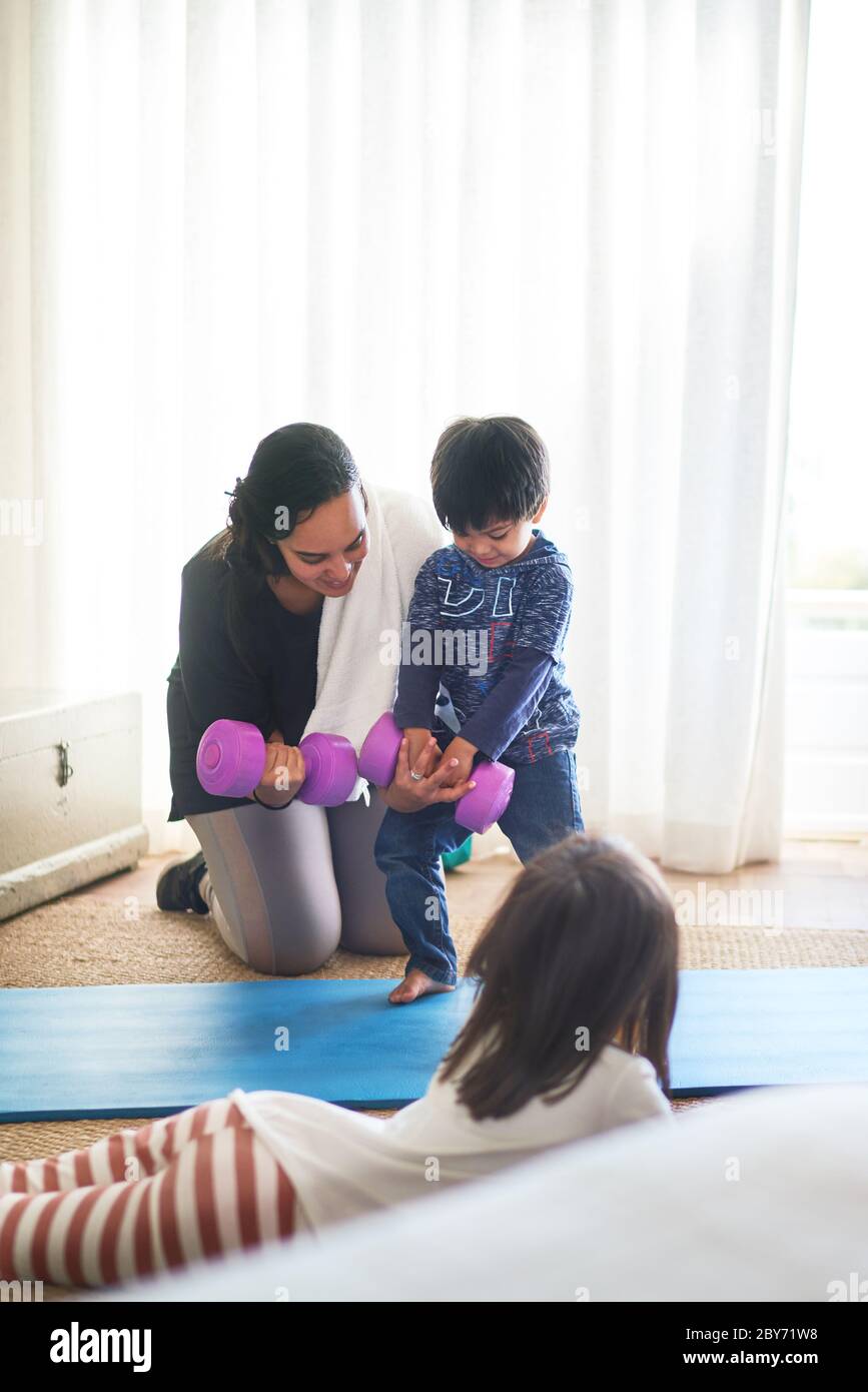 Mutter und Kinder trainieren mit Hanteln im Wohnzimmer Stockfoto