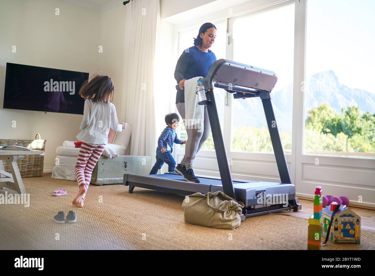 Kinder laufen um Mutter Training auf dem Laufband Stockfoto