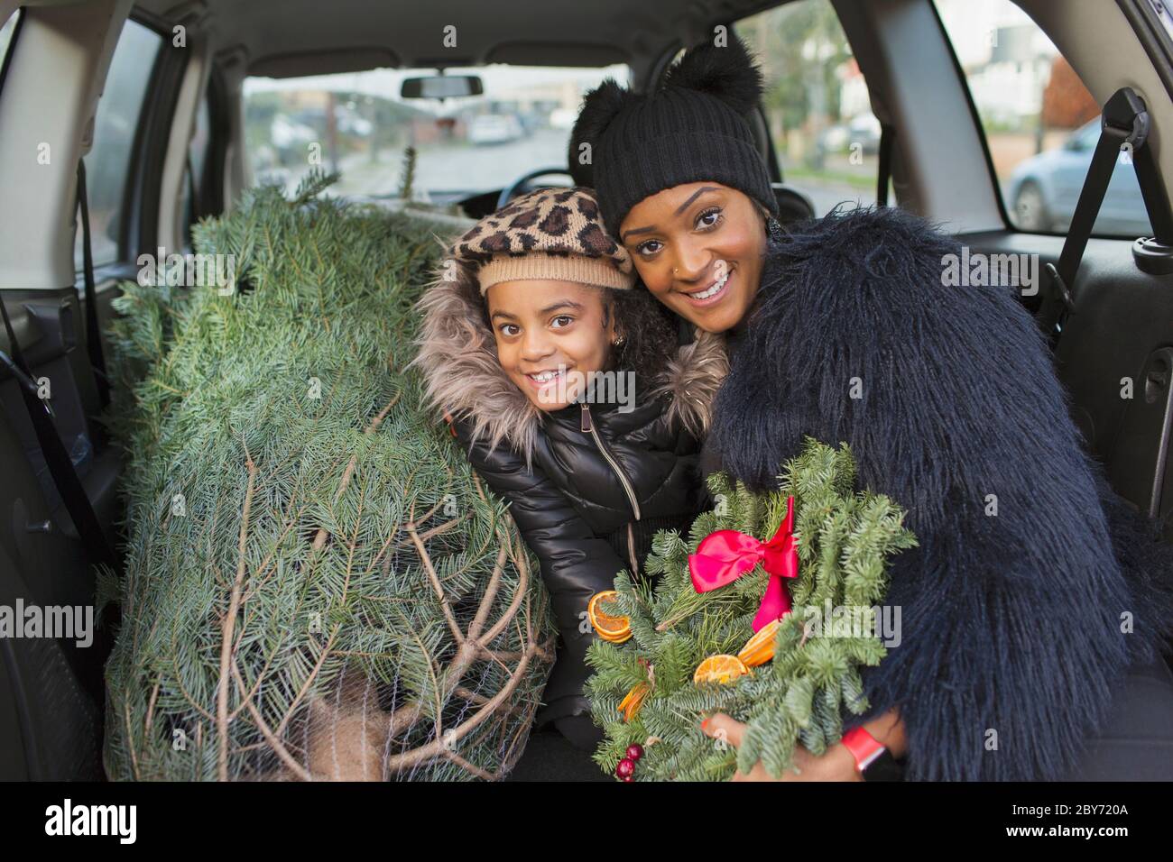 Portrait glückliche Mutter und Tochter mit Weihnachtsbaum im Auto Stockfoto