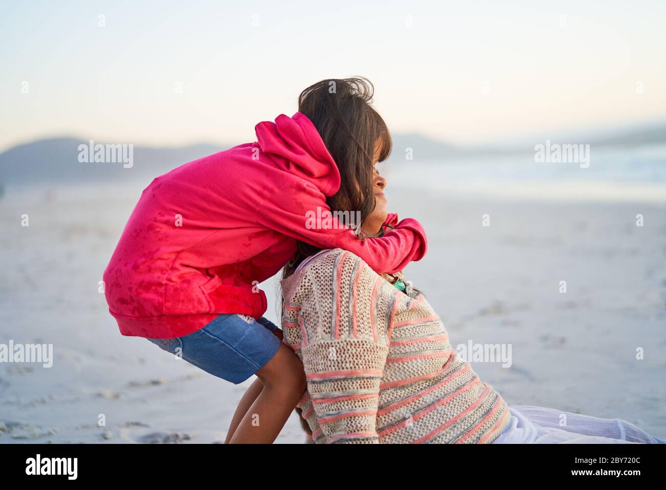 Liebevolle Tochter umarmt Mutter am Strand Stockfoto