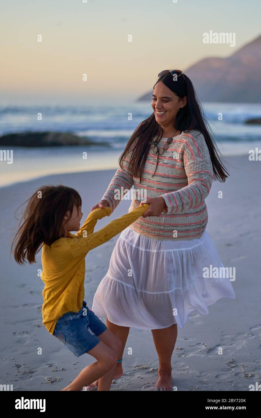 Verspielte Mutter und Tochter tanzen am Strand Stockfoto