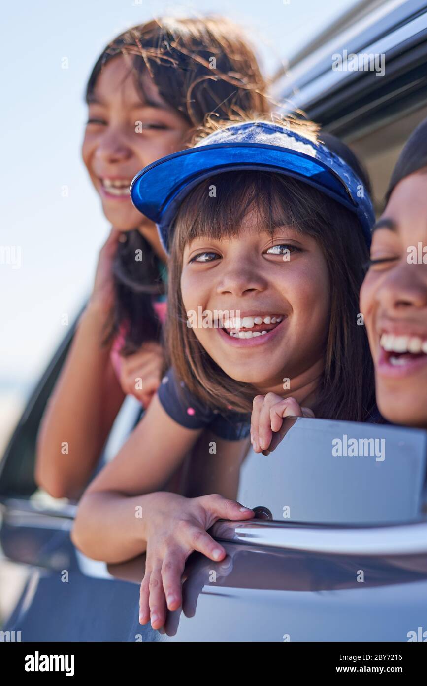 Glückliche Schwestern und Bruder lehnen sich aus sonnigen Autofenster Stockfoto