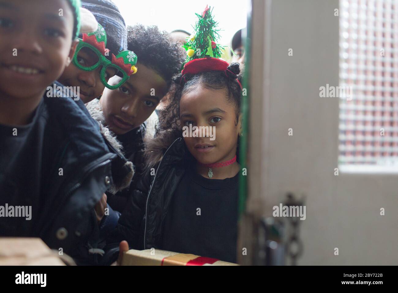 Portrait Brüder und Schwester mit Weihnachtsgeschenken vor der Tür Stockfoto