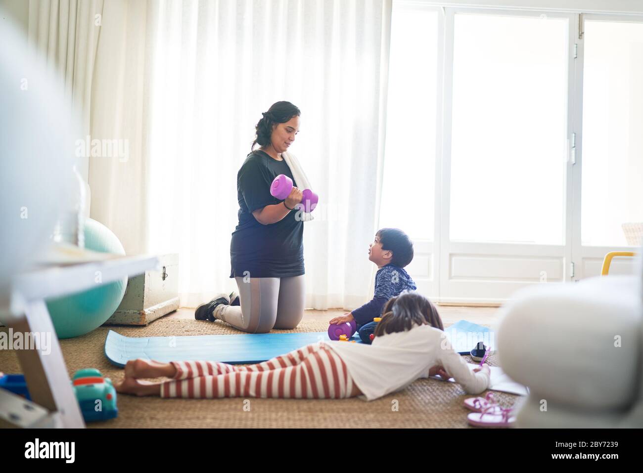 Junge beobachten Mutter Übung mit Hanteln im Wohnzimmer Stockfoto