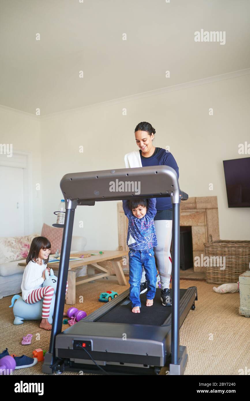 Mutter und Sohn gehen auf dem Laufband im Wohnzimmer Stockfoto