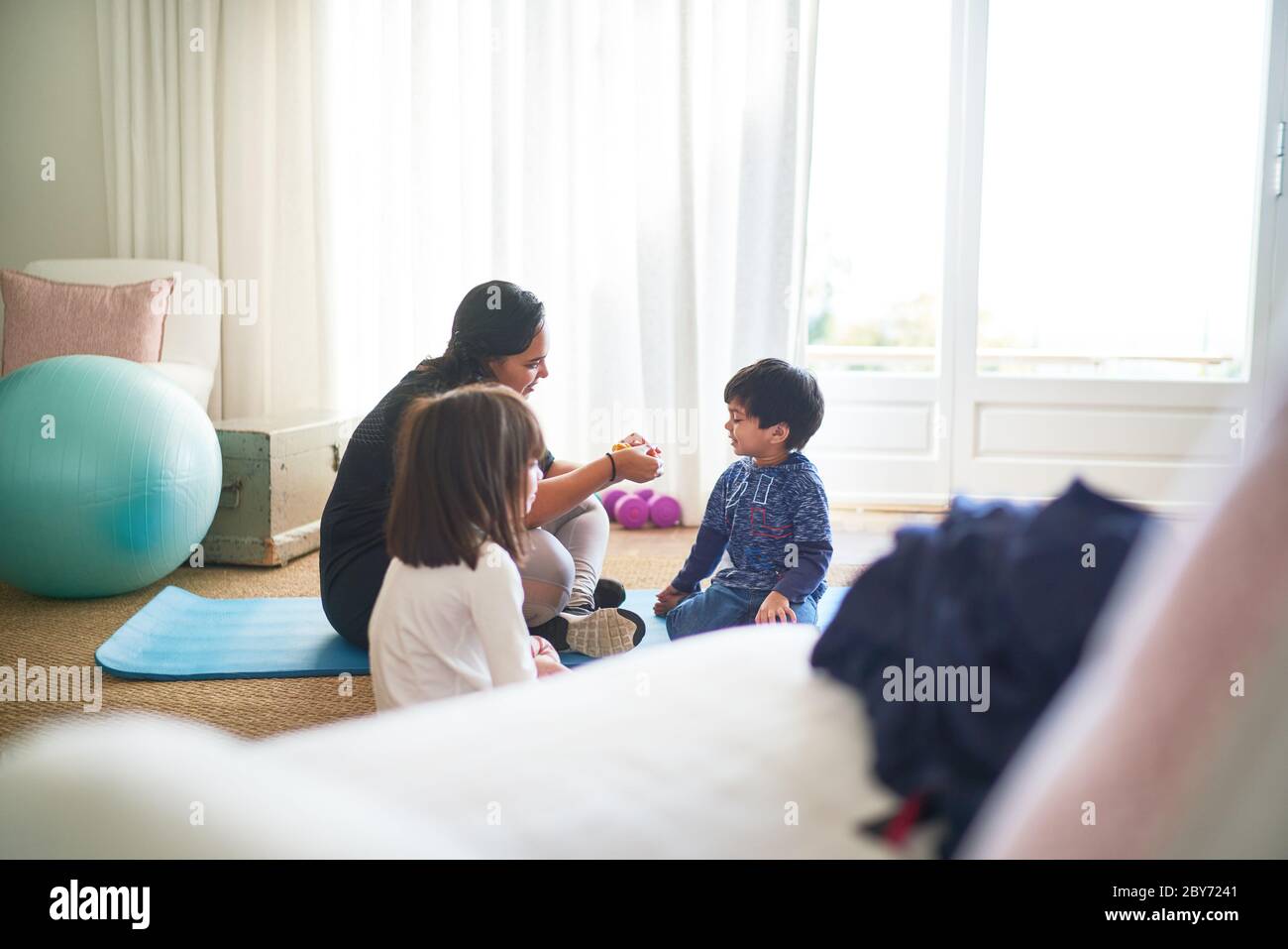 Mutter und Kinder trainieren auf Yoga-Matte im Wohnzimmer Stockfoto