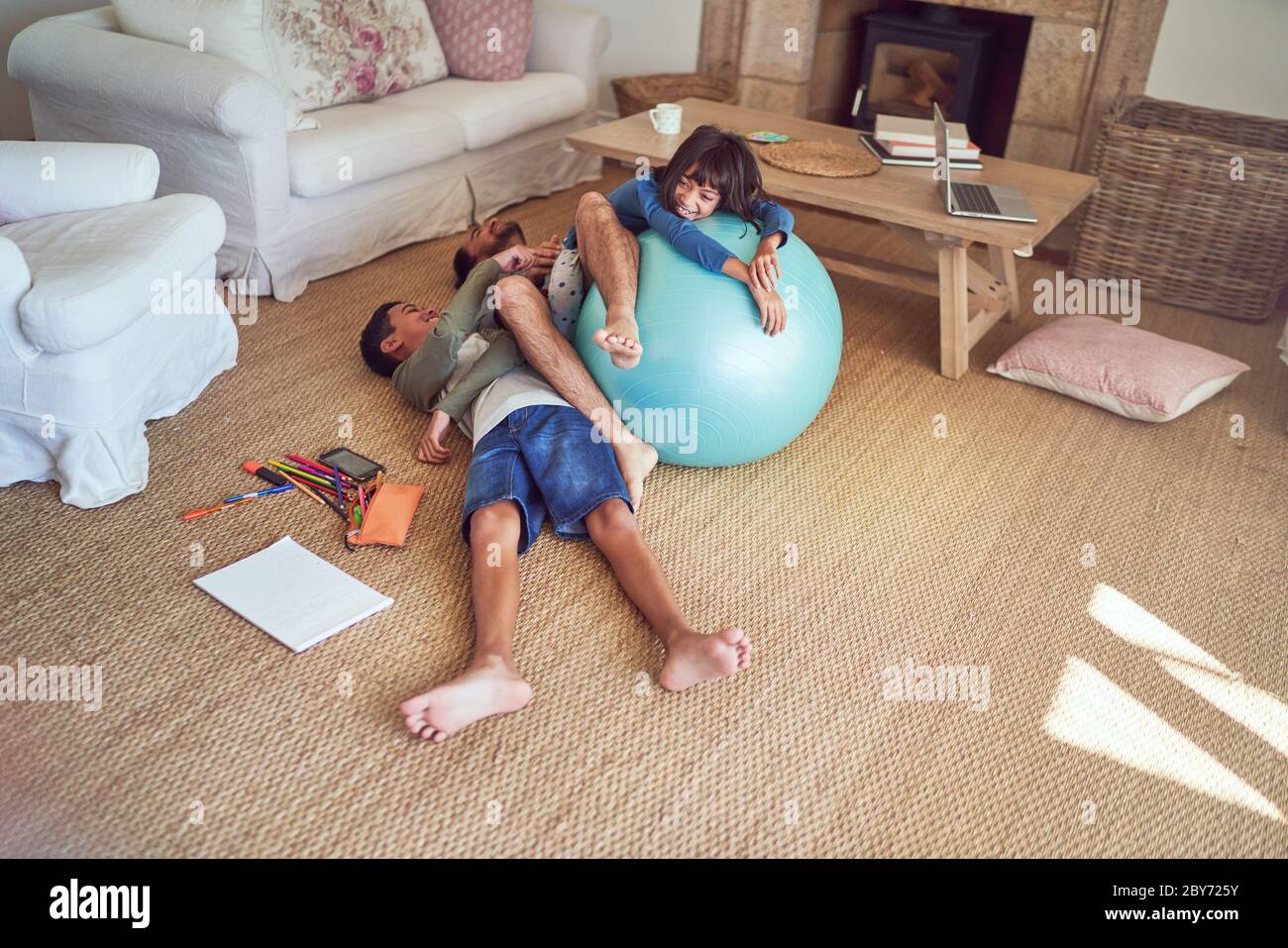 Verspielter Vater und Kinder mit Fitnessball auf Wohnzimmerboden Stockfoto