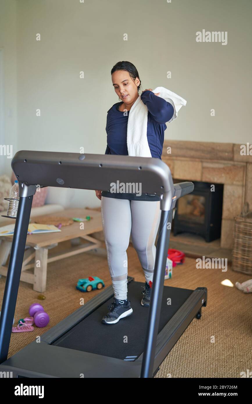 Frau, die auf dem Laufband im Wohnzimmer trainiert Stockfoto