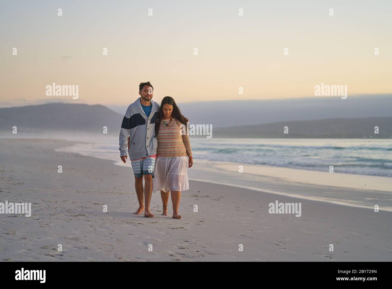 Liebevolles Paar, das am ruhigen Meeresstrand spazieren geht Stockfoto