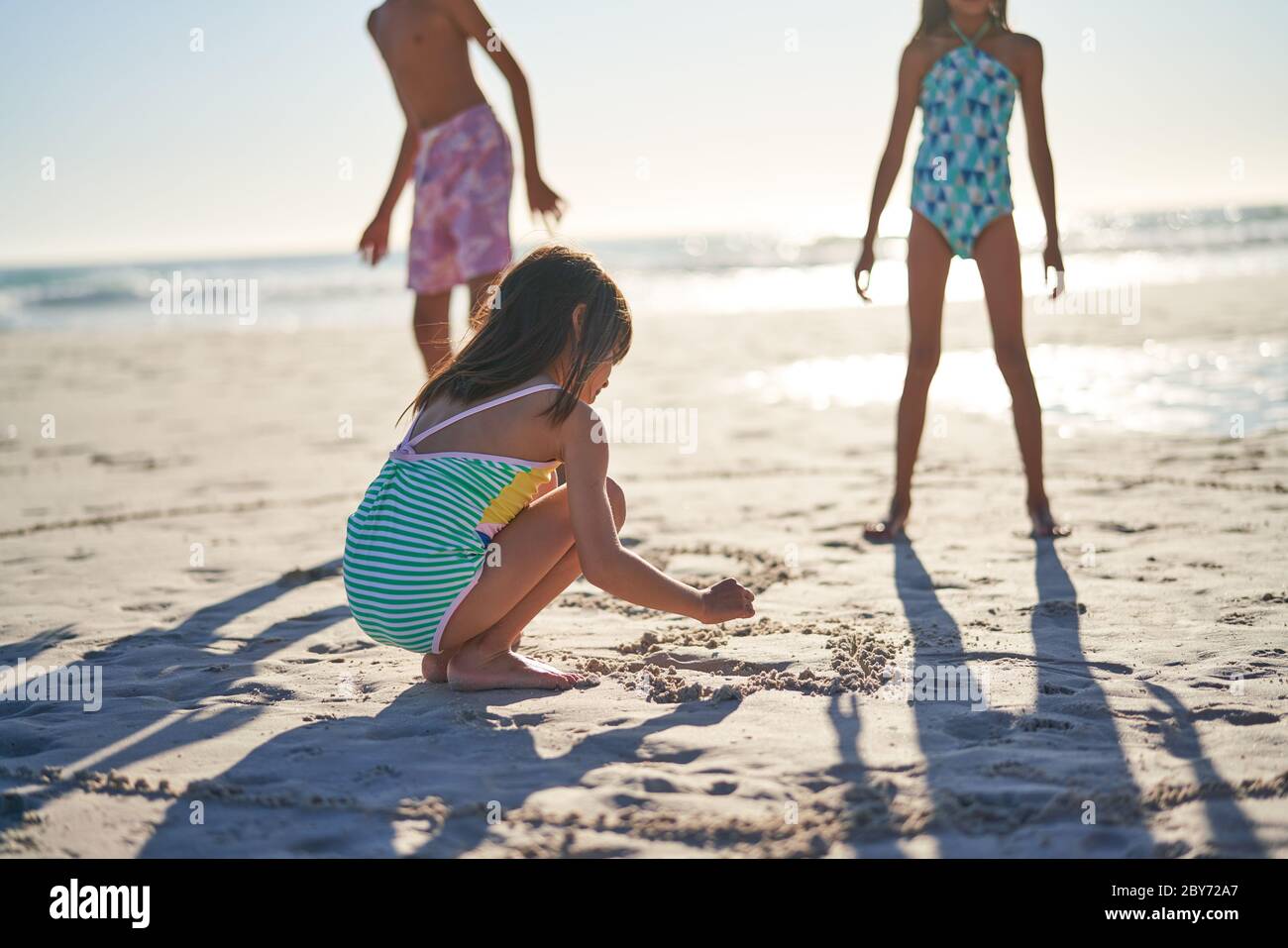 Mädchen Zeichnung Herz im Sand am sonnigen Strand Stockfoto