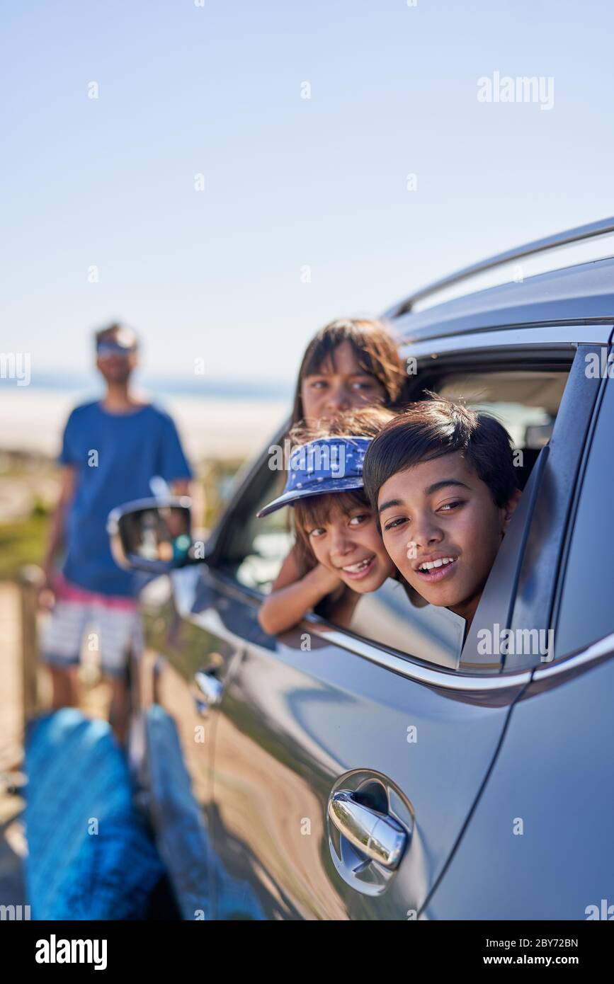 Glückliche Kinder, die sich auf dem Parkplatz am Strand aus dem Fenster lehnen Stockfoto