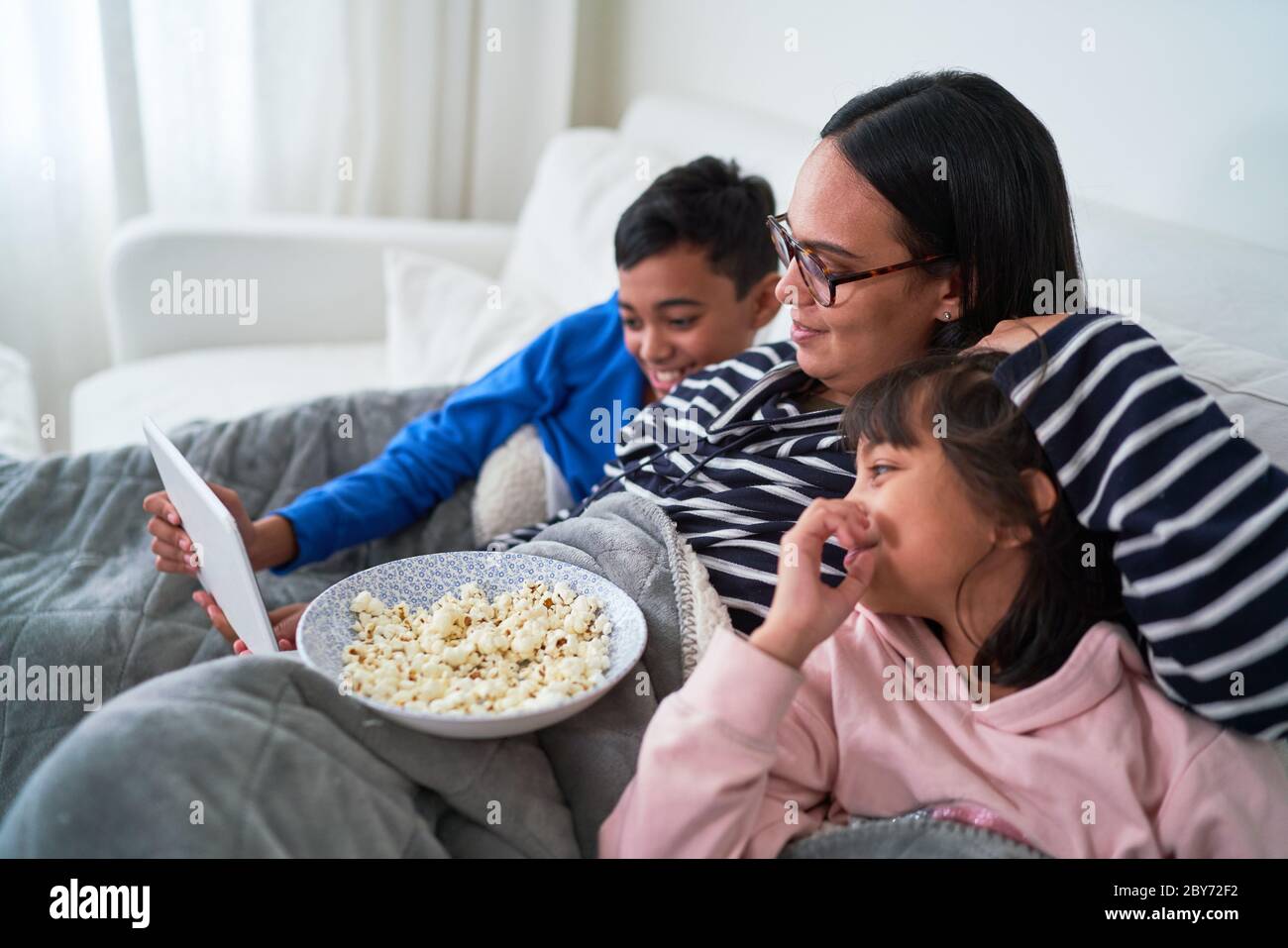 Mutter und Kinder mit Popcorn beim Film auf einem digitalen Tablet Stockfoto