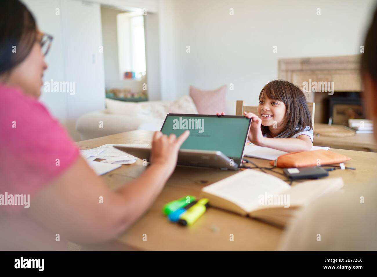 Tochter ablenkende Mutter arbeitet am Laptop Stockfoto