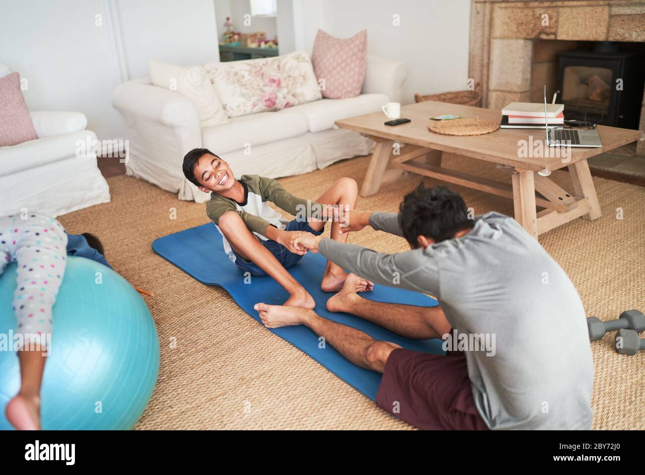 Verspielte Vater und Sohn trainieren auf Yoga-Matte im Wohnzimmer Stockfoto