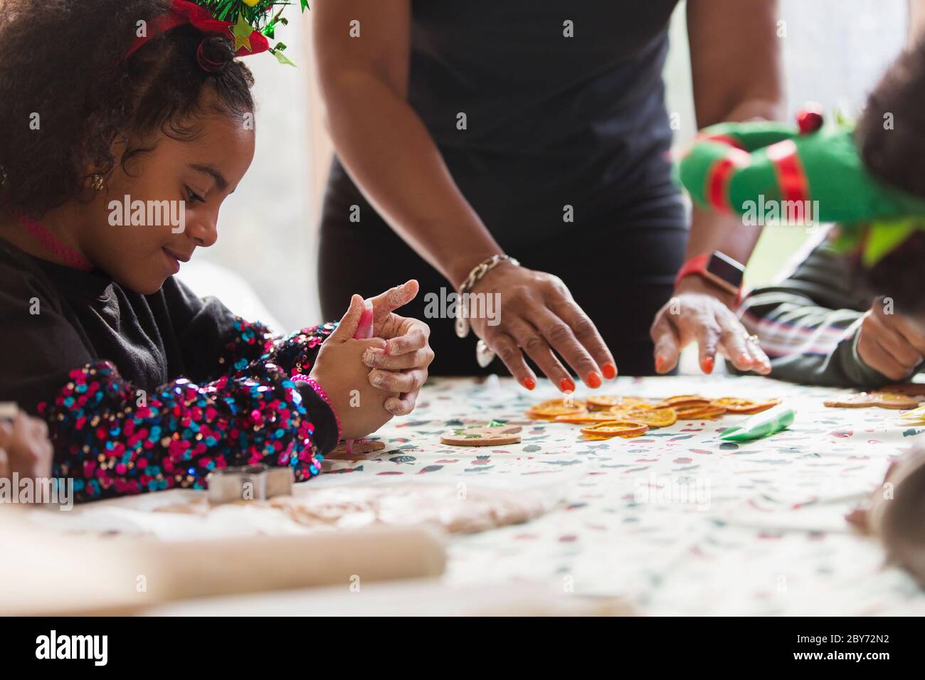 Mädchen Dekoration Weihnachtskekse mit Familie am Tisch Stockfoto