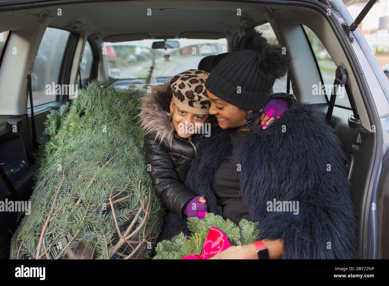 Portrait glückliche Mutter und Tochter im Auto mit Weihnachtsbaum Stockfoto