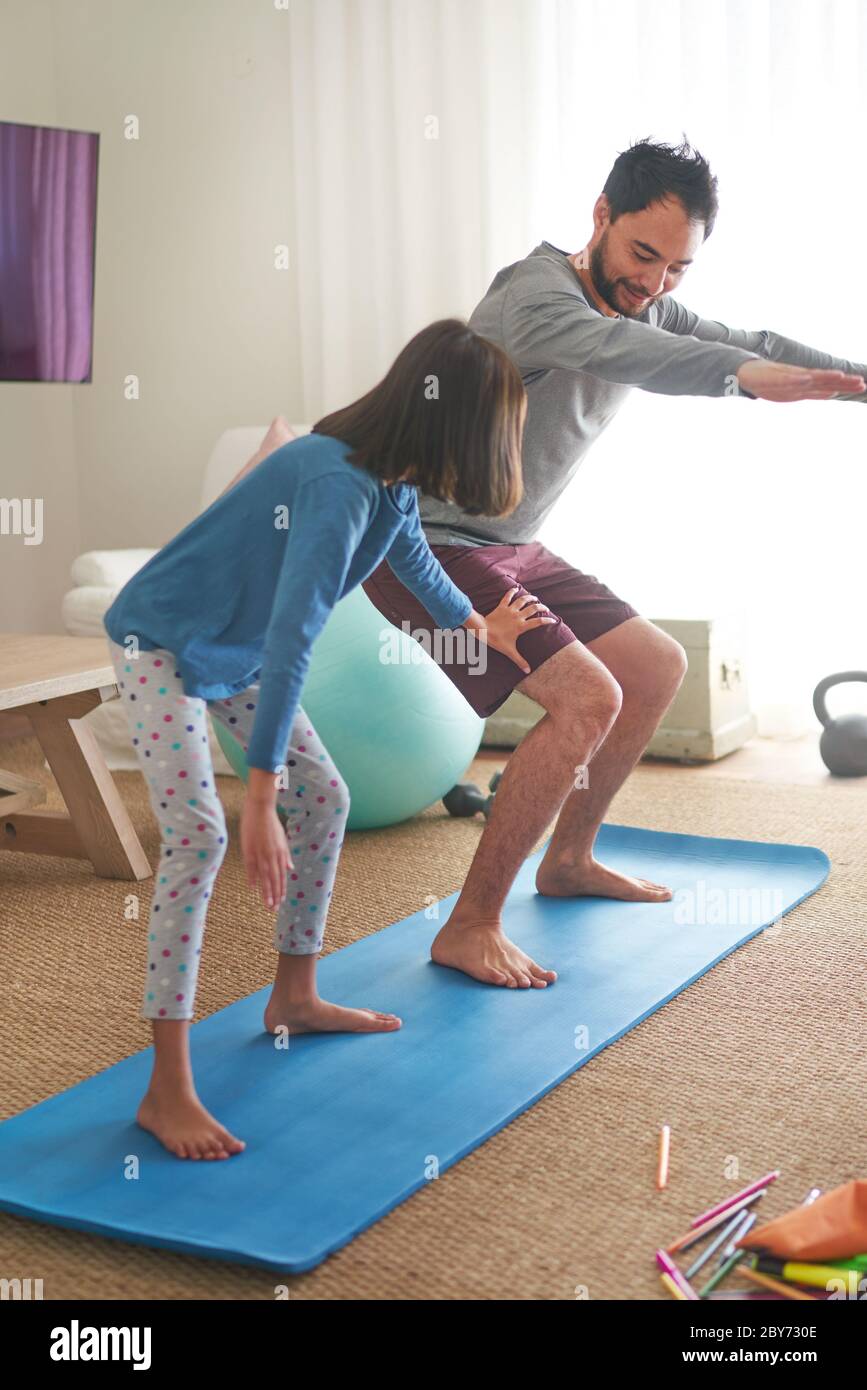 Vater und Tochter trainieren auf Matte im Wohnzimmer Stockfoto