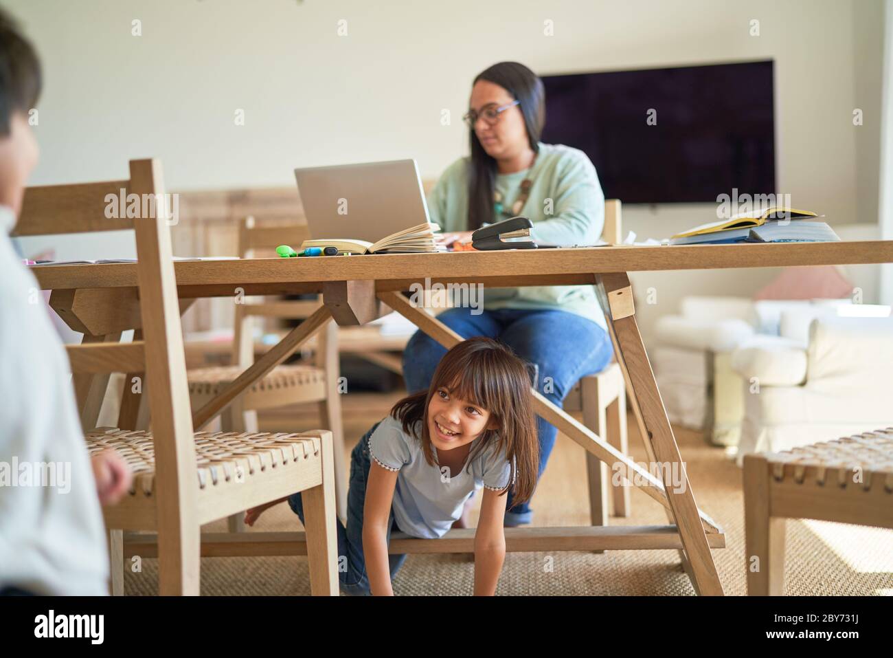 Kinder, die unter der Mutter am Esstisch spielen Stockfoto