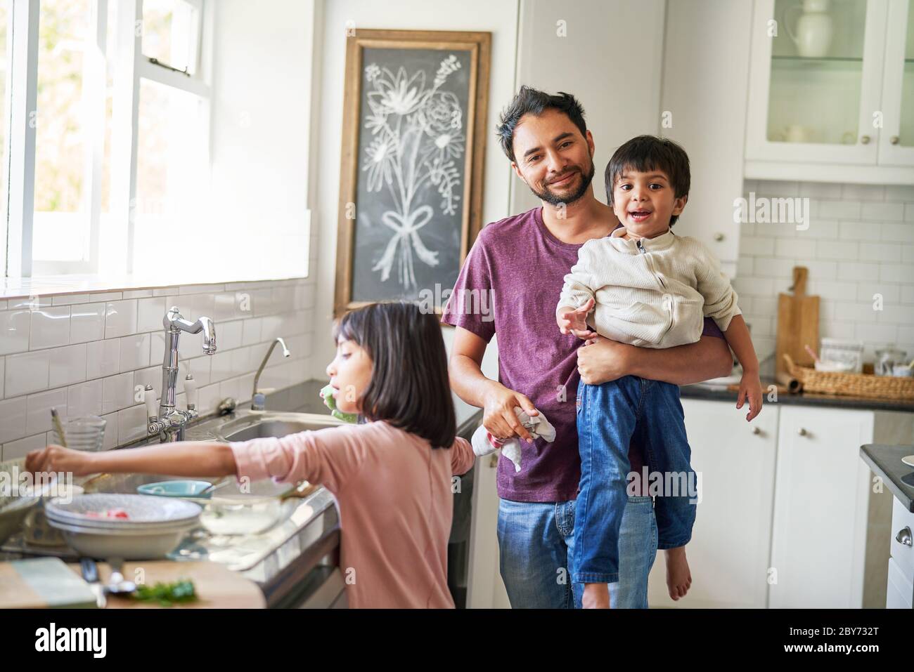 Portrait glücklicher Vater und Kinder beim Geschirr in der Küche Stockfoto