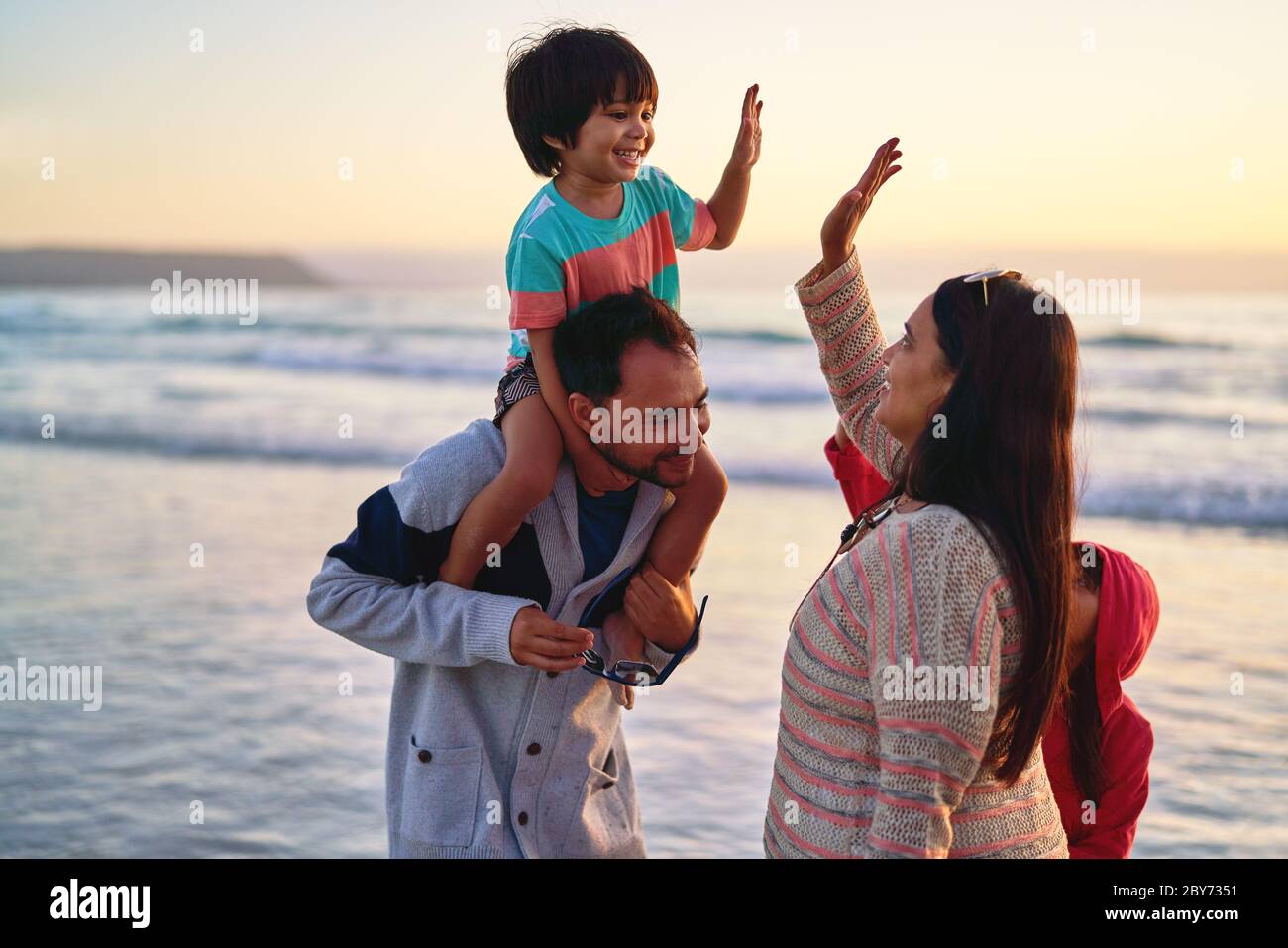 Glückliche Familie High-Fiving am Ocean Beach Stockfoto