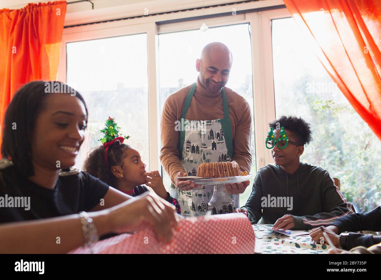 Vater serviert Weihnachtskuchen an der Familie am Tisch Stockfoto