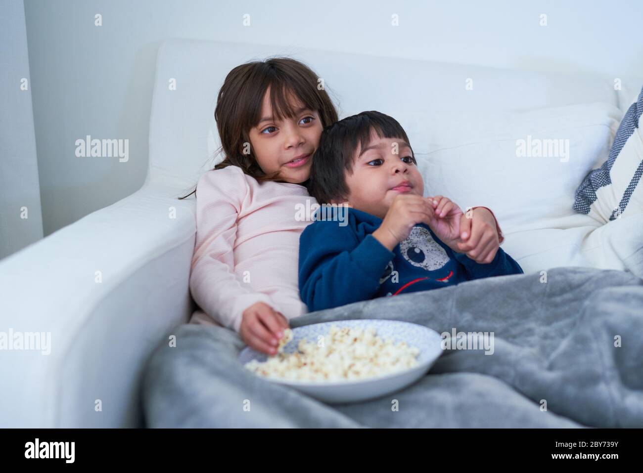 Liebevoller Bruder und Schwester essen Popcorn und Fernsehen auf dem Sofa Stockfoto