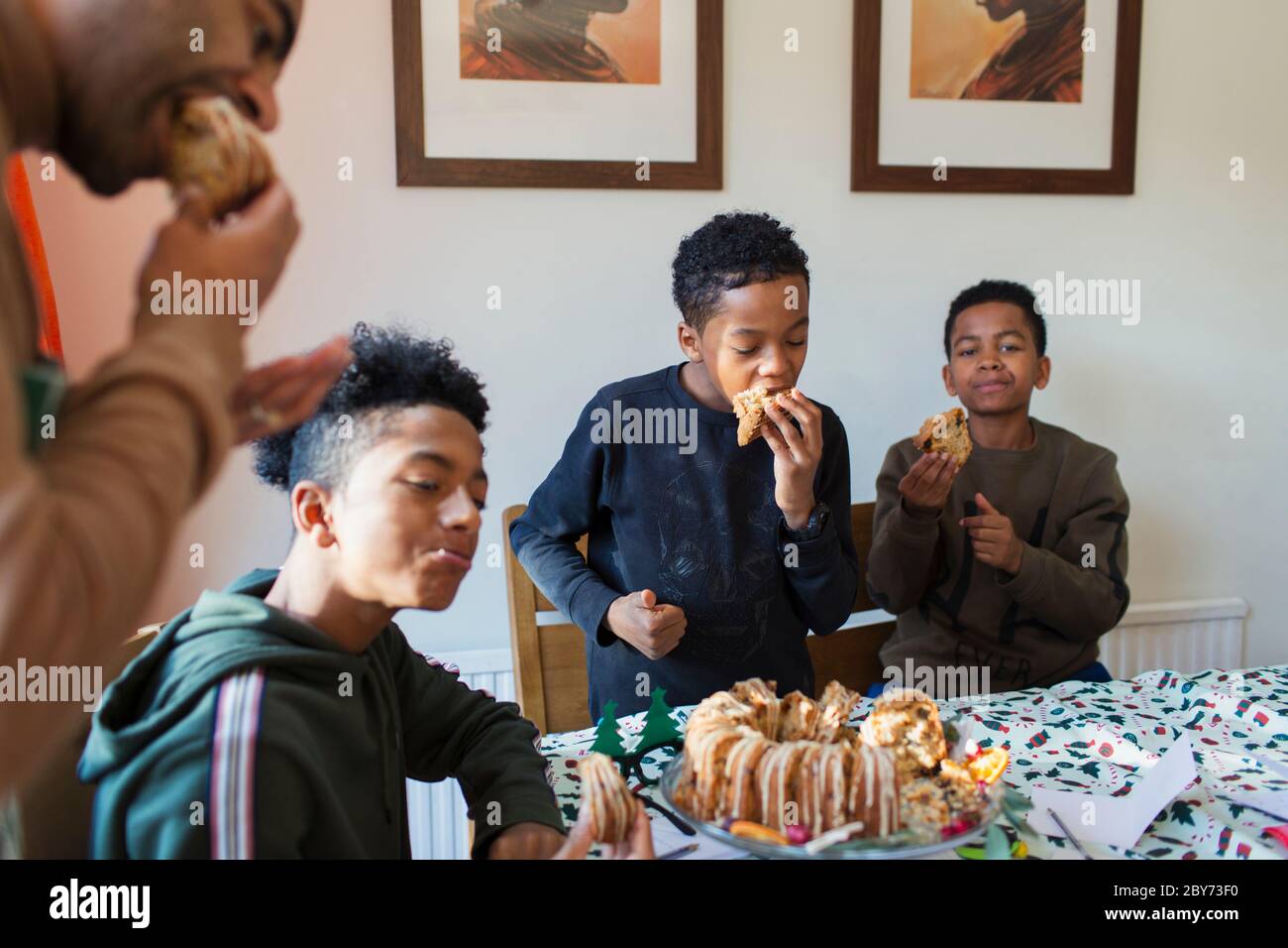 Vater und Söhne essen Weihnachtskuchen am Tisch Stockfoto
