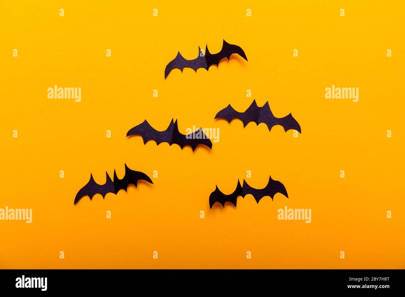 Basteln für die Konzeptfeier von Halloween. Figuren einer schwarzen Fledermaus, aus schwarzem Papier auf gelbem Hintergrund geschnitten. Für Text platzieren Mock Up Top View Stockfoto