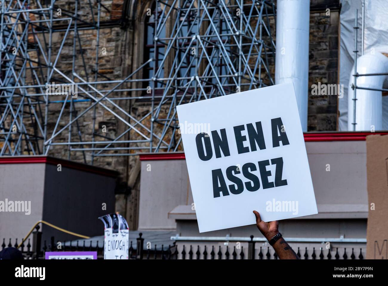 Ein Protestler hält ein französischsprachiges Schild, das "wir haben genug" bedeutet, während Tausende sich in Ottawa, Kanada, versammeln, um gegen Polizeigewalt und Rassismus zu protestieren. Stockfoto